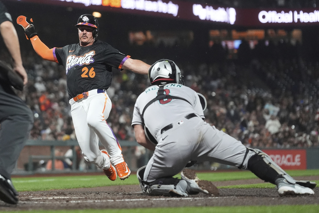 San Francisco Giants' Matt Chapman, left, slides home to score against Arizona Diamondbacks catcher James McCann during the fourth inning of a baseball game in San Francisco, Tuesday, Sept. 9, 2025. (AP Photo/Jeff Chiu)