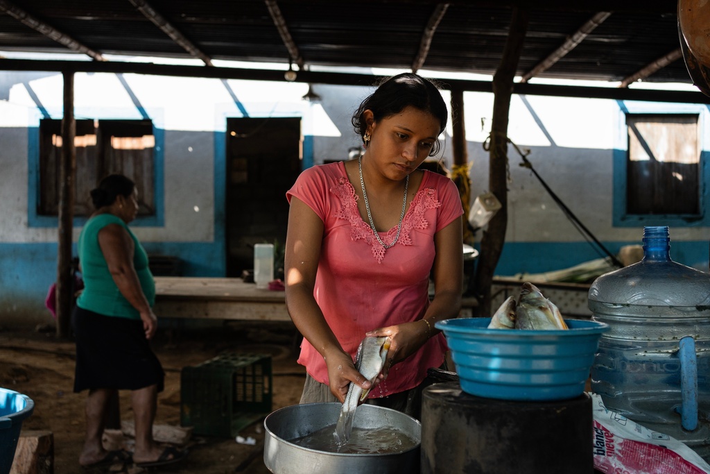 Ana Carolina Hernández cleans fish inside her kitchen to prepare them for cooking in Los Arrecifes, Mexico, Oct. 27, 2025. (AP Photo/Felix Marquez)