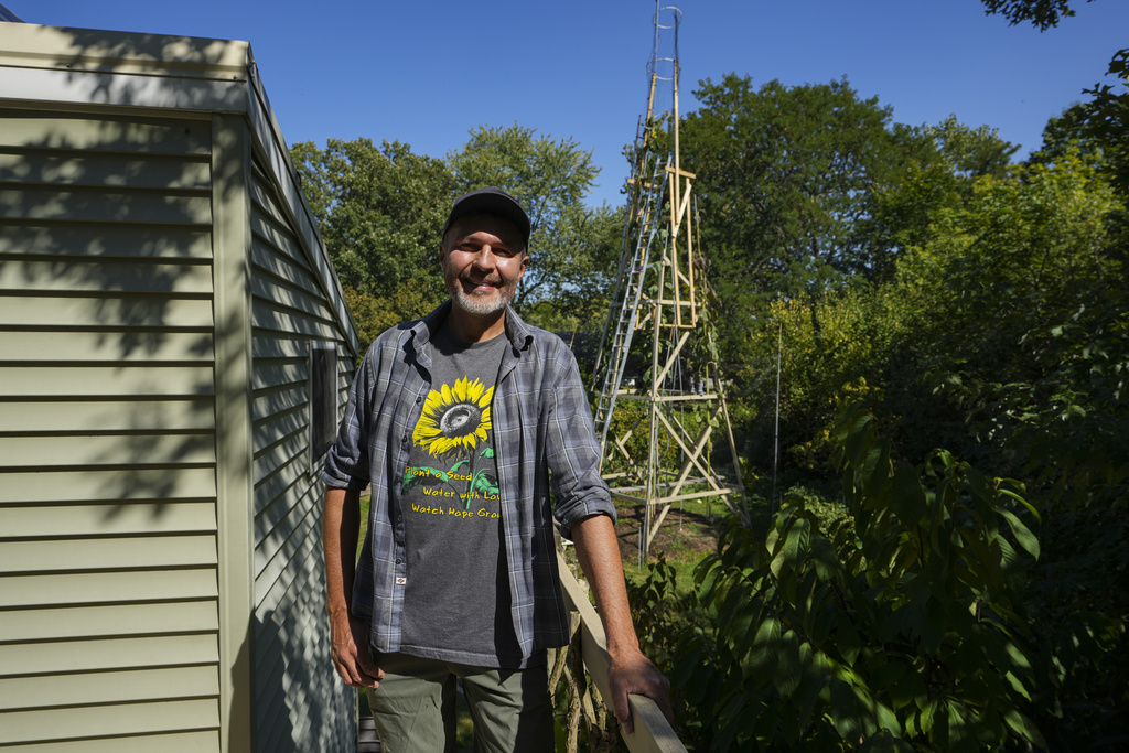 Alex Babich, pose in front of the structure that surrounds his nearly 36-feet high sunflower that holds the world record for the tallest flower at his home in Fort Wayne, Ind., Thursday, Sept. 11, 2025. (AP Photo/Michael Conroy)