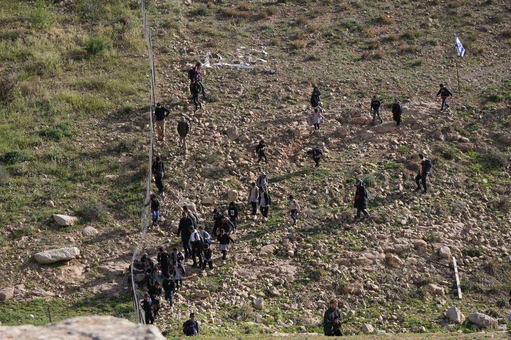 Palestinian students walk to school along a fence separating their village from the nearby Israeli settlement of Carmel, near the West Bank village of Umm al-Khair, Tuesday, April 14, 2026. (AP Photo/Mahmoud Illean)