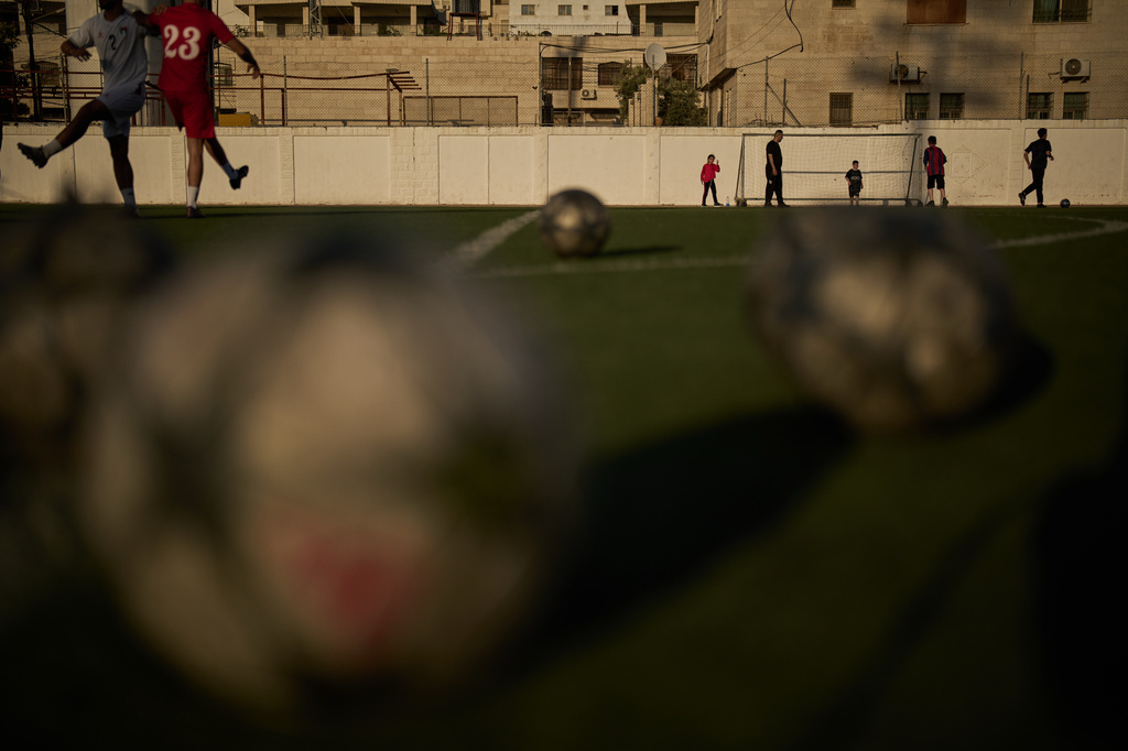 Palestinian children play as youths from a local soccer academy take part in a training session at Jamal Ghanem Stadium in the West Bank city of Tulkarem, Thursday, June 4, 2026. (AP Photo/Leo Correa)