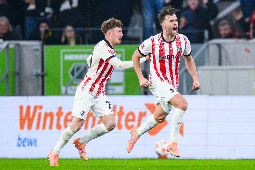 Freiburg's Lucas Hoeler, right, celebrates after scoring his side's first goal during the German Bundesliga soccer match between SC Freiburg and Borussia Dortmund in Freiburg, Germany, Sunday, Dec. 14, 2025. (Tom Weller/dpa via AP)