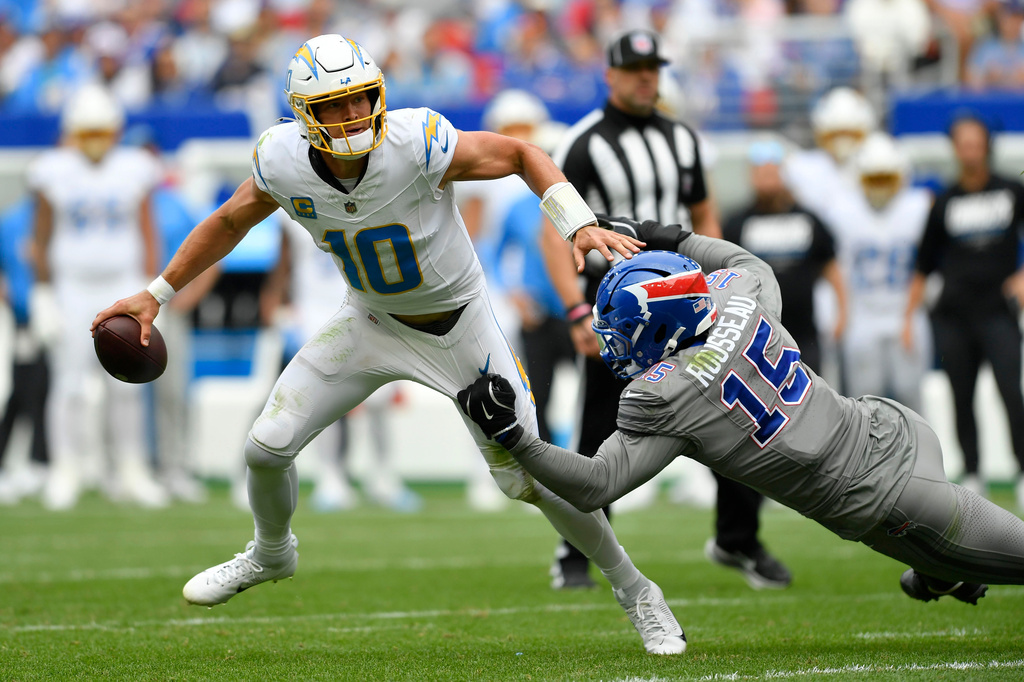 Los Angeles Chargers quarterback Justin Herbert (10) runs from Buffalo Bills linebacker Greg Rousseau (15) during the second half of an NFL football game, Sunday, Sept. 27, 2026, in Orchard Park, N.Y. (AP Photo/Adrian Kraus)