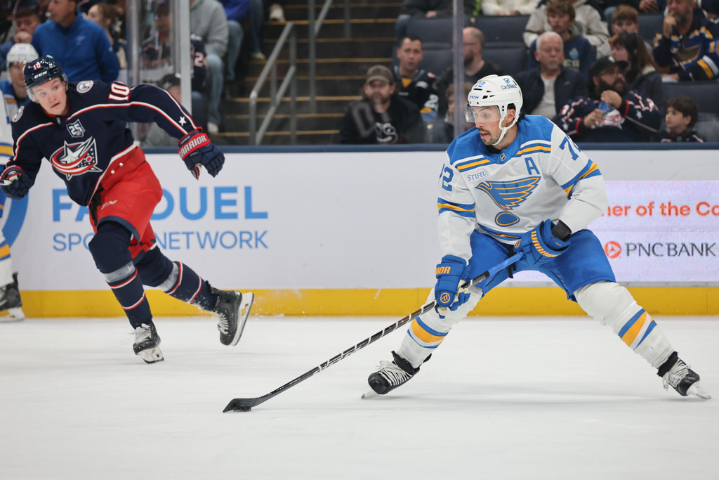 St. Louis Blues defenseman Justin Faulk, right, controls the puck in front of Columbus Blue Jackets forward Dmitri Voronkov during the first period of an NHL hockey game in Columbus, Ohio, Saturday, Nov. 1, 2025. (AP Photo/Paul Vernon)