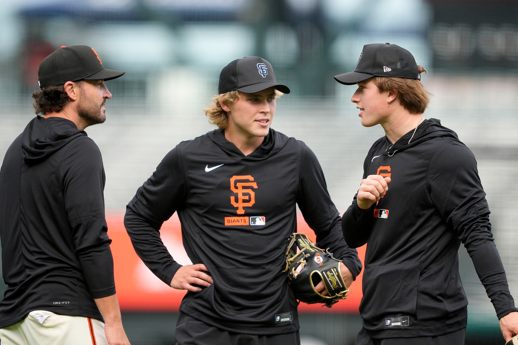 San Francisco Giants manager Tony Vitello, left, talks with San Jose Sharks NHL hockey players Will Smith, center, and Macklin Celebrini, right, during batting practice before a baseball game between the Giants and the Arizona Diamondbacks in San Francisco, Friday, Aug. 28, 2026. (AP Photo/Tony Avelar)