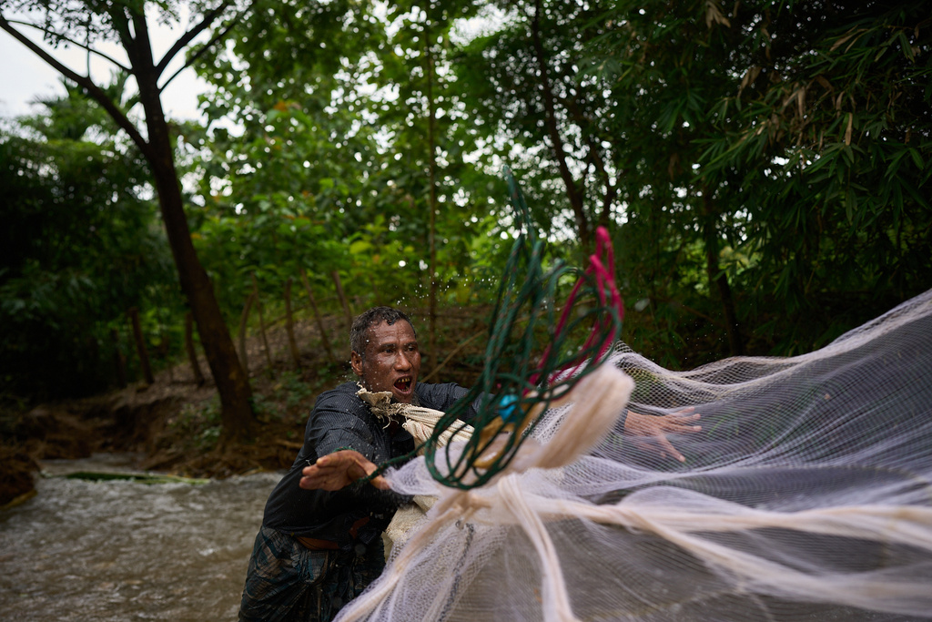 Mahmud Karmar throws a fishing net into the river near the Mae La refugee camp in the Tak province of Thailand, Thursday, Aug. 28, 2025. (AP Photo/Bram Janssen)
