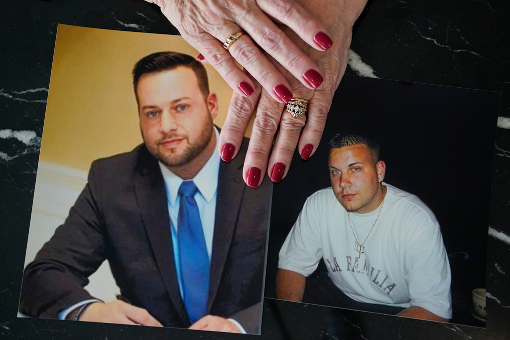 FILE - Cheryl Juaire holds photos of her sons, both of whom died from overdoses, Sean Merrill, left, and Corey Merrill, after making a statement during a hearing in New York on March 10, 2022. (AP Photo/Seth Wenig, File)