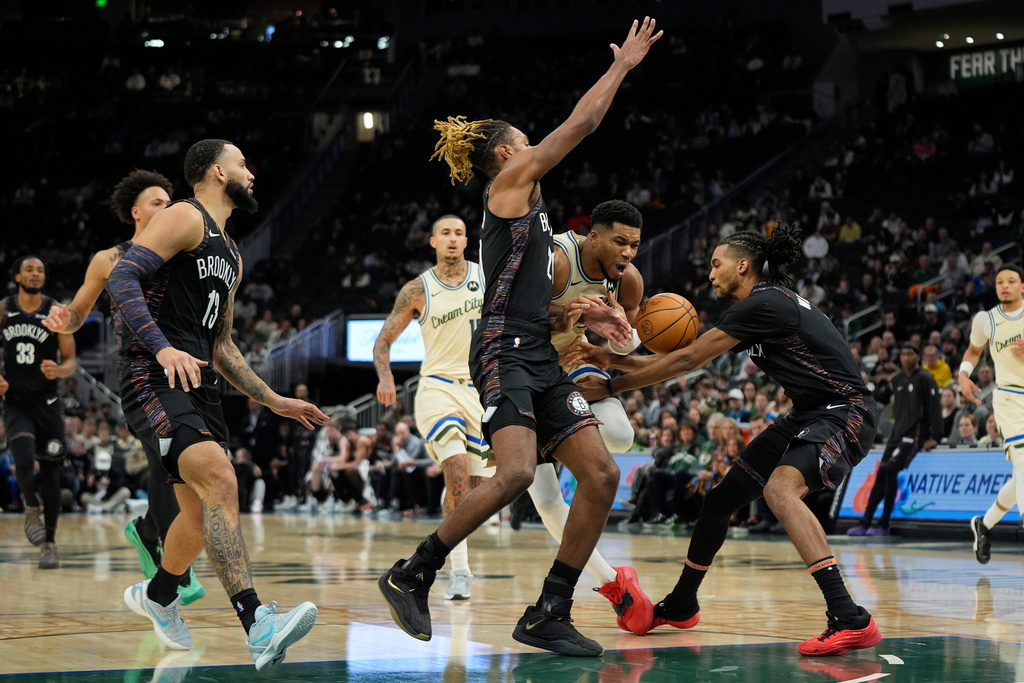 Milwaukee Bucks' Giannis Antetokounmpo controls the ball as he drives between Brooklyn Nets' Noah Clowney, left, and Ziaire Williams, right, during the first half of an NBA basketball game Saturday, Nov. 29, 2025, in Milwaukee. (AP Photo/Aaron Gash)
