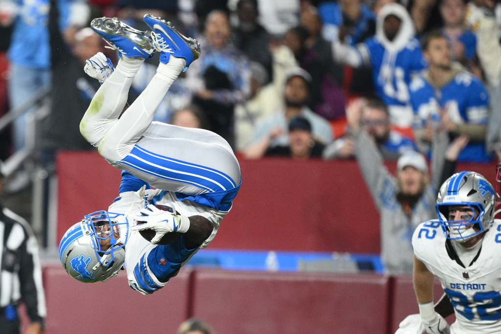 Detroit Lions wide receiver Jameson Williams (1) scores as teammate tight end Ross Dwelley (82) watches during the second half of an NFL football game against the Washington Commanders Sunday, Nov. 9, 2025, in Landover, Md. (AP Photo/Nick Wass)