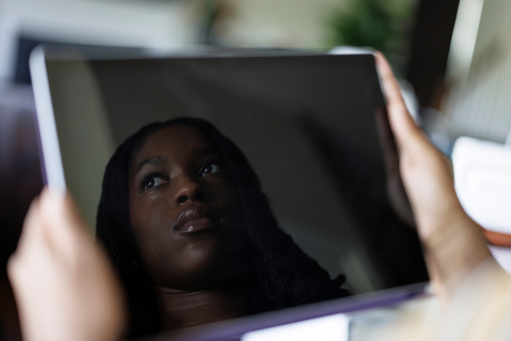 Faith Maeba, a student at Virginia Commonwealth University, poses for a portrait with her tablet at home Monday, July 20, 2026, in Stafford, Va. (AP Photo/Moriah Ratner)