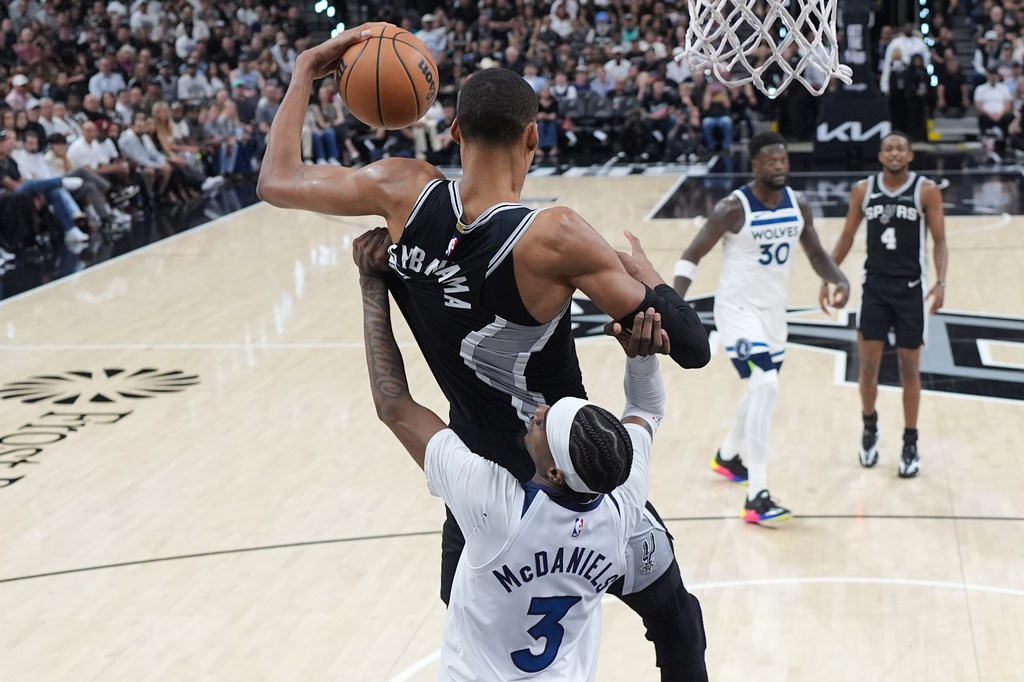 San Antonio Spurs forward Victor Wembanyama (1) pulls down a rebound over Minnesota Timberwolves forward Jaden McDaniels (3) during the first half of Game 5 of an NBA basketball second-round playoffs series in Minneapolis, Tuesday, May 12, 2026. (AP Photo/Eric Gay)