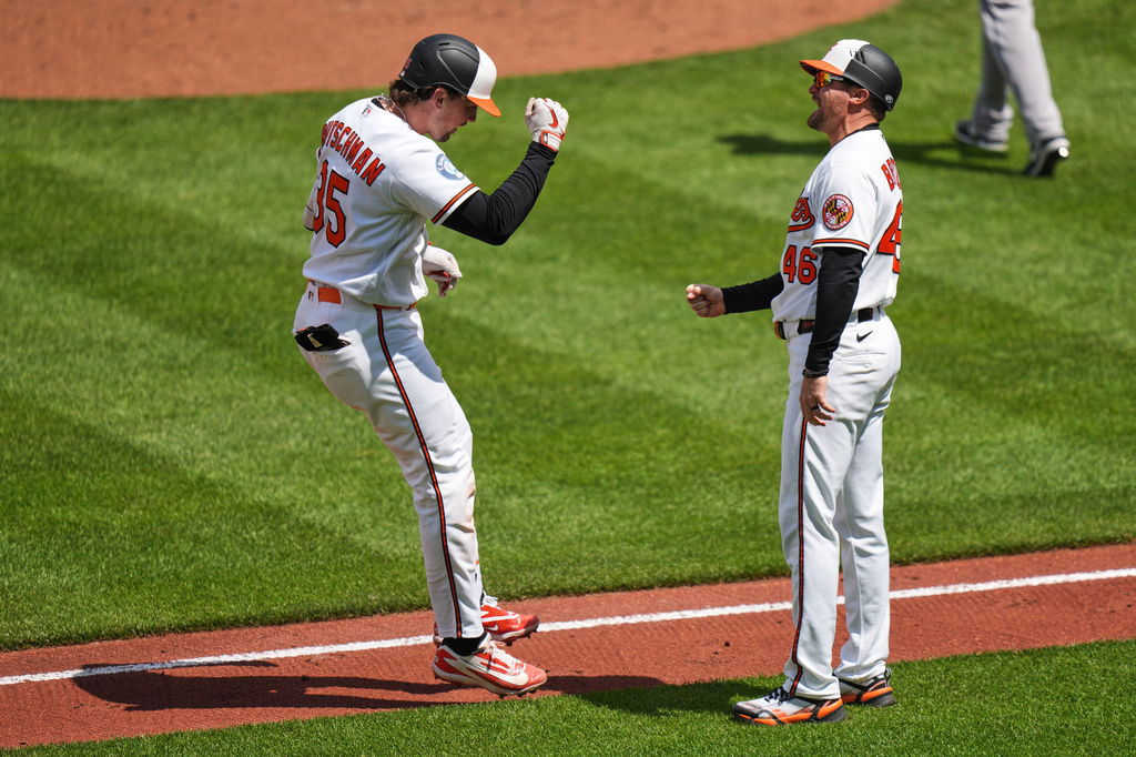 Baltimore Orioles' Adley Rutschman (35) celebrates with third base coach Buck Britton (46) after hitting a grand slam during the fifth inning in the first baseball game of a doubleheader against the Houston Astros, Thursday, April 30, 2026, in Baltimore. (AP Photo/Stephanie Scarbrough)