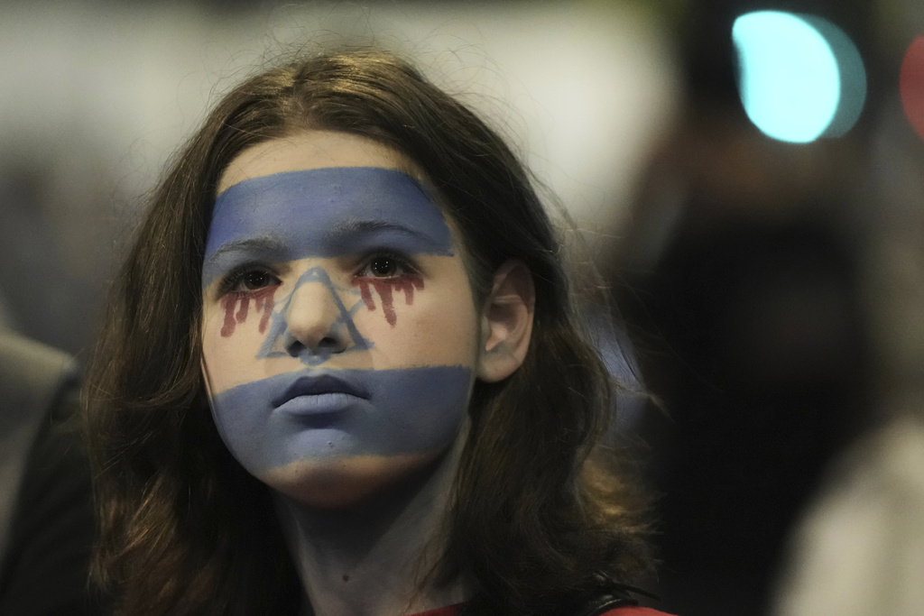 A woman with her face painted in the colors of the Israeli flag takes part in a protest demanding the end of the war, the immediate release of hostages held by Hamas in the Gaza Strip, and against Prime Minister Benjamin Netanyahu's government in Tel Aviv, Saturday, Aug. 16, 2025. (AP Photo/Mahmoud Illean)