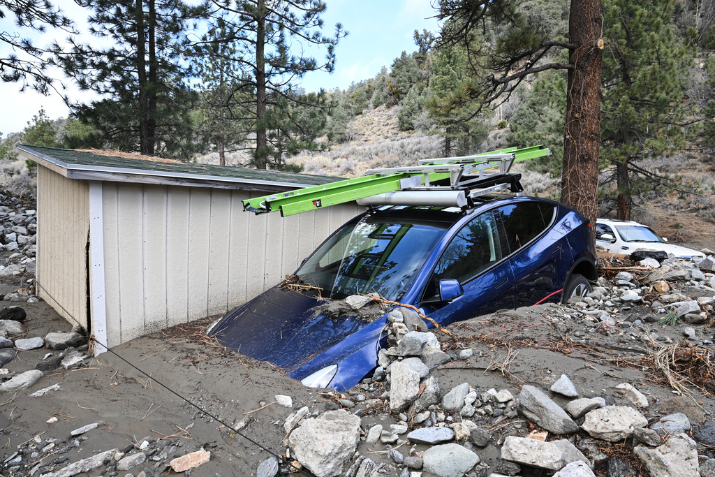A car is buried in mud after a series of storms Thursday, Dec. 25, 2025, in Wrightwood, Calif. (AP Photo/William Liang)
