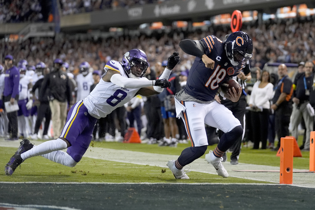 Chicago Bears quarterback Caleb Williams (18) scores past Minnesota Vikings cornerback Jeff Okudah (8) on a 9-yard run during the first half of an NFL football game Monday, Sept. 8, 2025, in Chicago. (AP Photo/Erin Hooley)