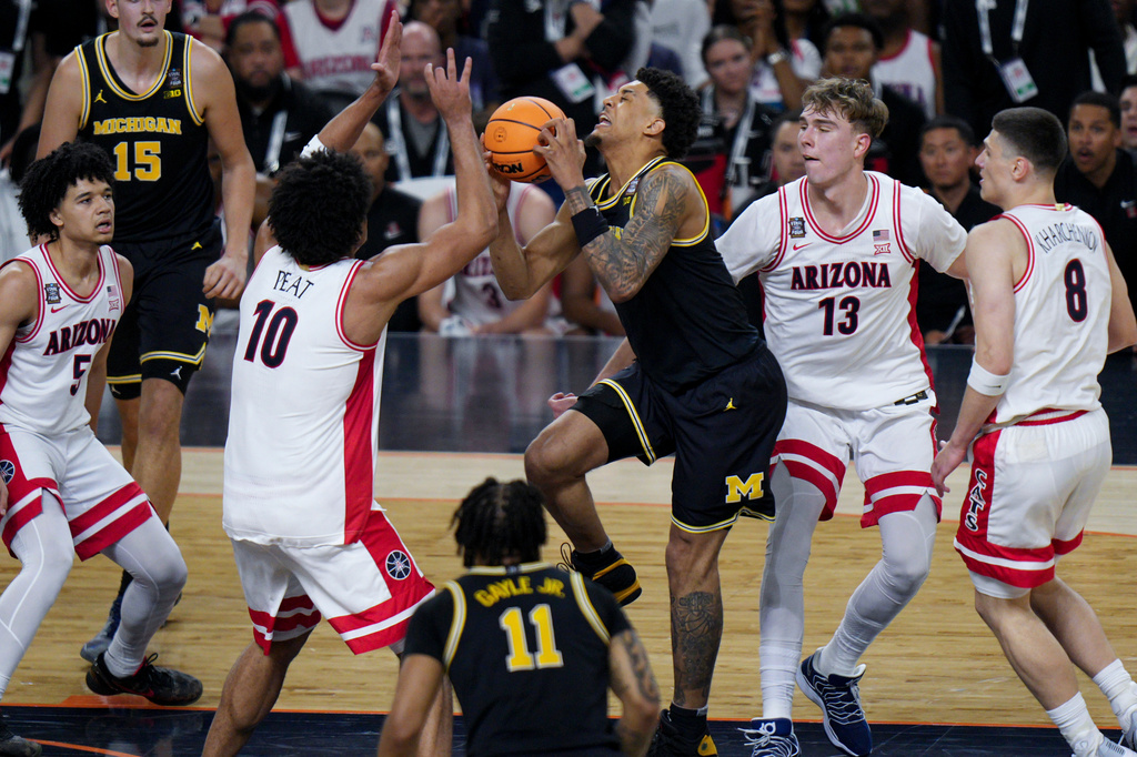 Michigan forward Yaxel Lendeborg, center, is injured on a play as Arizona center Motiejus Krivas (13) and forward Koa Peat (10) defend during the first half of an NCAA college basketball tournament semifinal game against Arizona at the Final Four, Saturday, April 4, 2026, in Indianapolis. (AP Photo/AJ Mast)