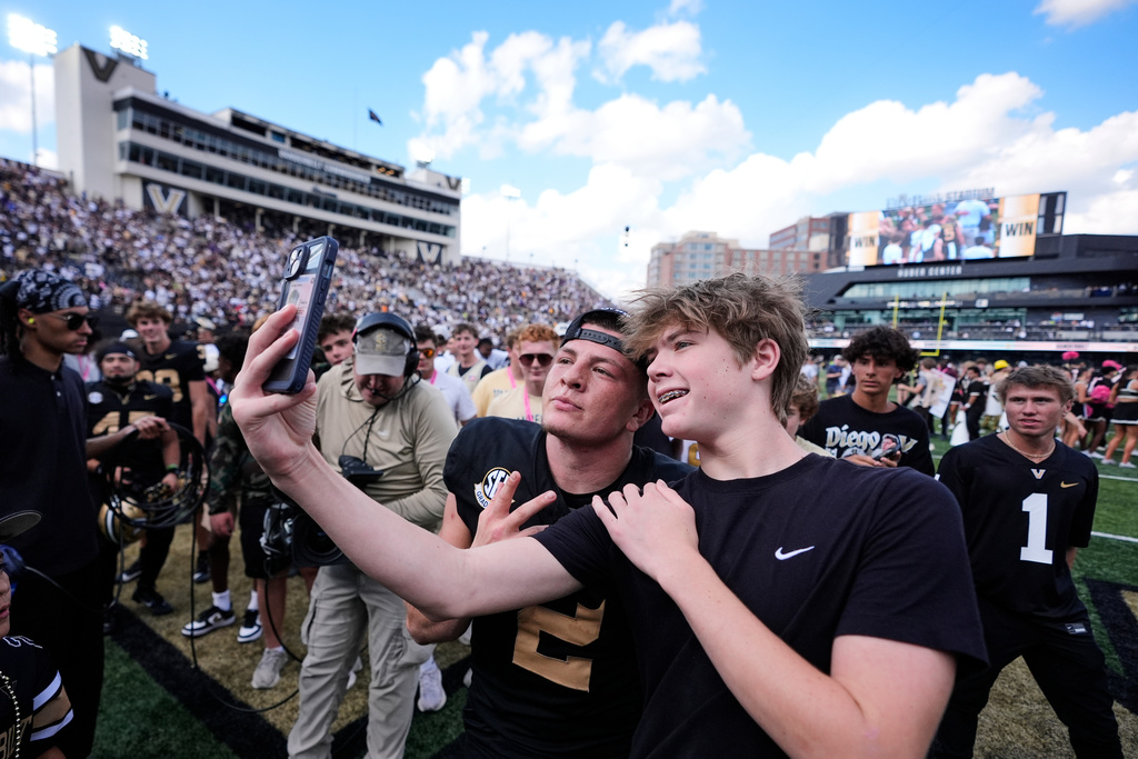 Vanderbilt quarterback Diego Pavia (2) poses with a fan after the team's win after an NCAA college football game against LSU, Saturday, Oct. 18, 2025, in Nashville, Tenn. (AP Photo/George Walker IV)