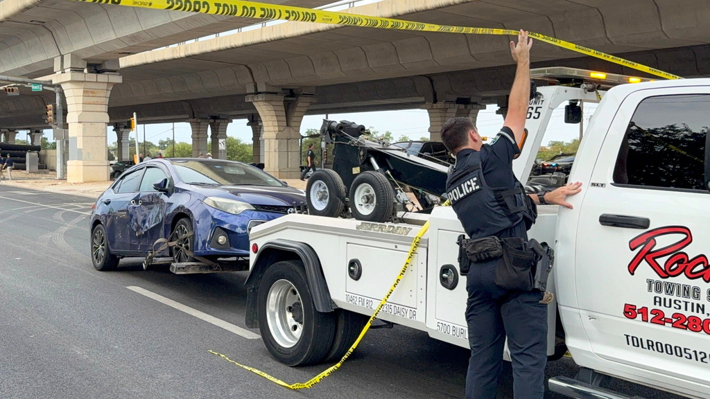 In this photo taken with a smart phone Police move a car from the area where an ICE officer shot a man in Austin, Texas, Sunday, Sept. 20, 2026. (AP Photo/Jesse Bedayn)