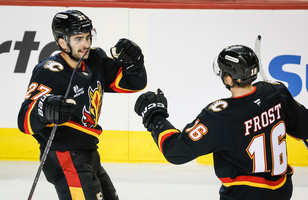 Calgary Flames' Matt Coronato, left, celebrates his goal with teammate Morgan Frost during third period NHL hockey action against the Minnesota Wild in Calgary on Thursday, Dec. 4, 2025. (Jeff McIntosh/The Canadian Press via AP)
