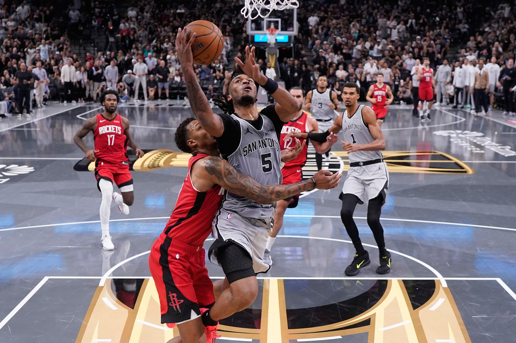 San Antonio Spurs guard Stephon Castle (5) is fouled by Houston Rockets forward Jabari Smith Jr. (10) as he drives to the basket during the first half of an NBA Cup basketball game in San Antonio, Friday, Nov. 7, 2025. (AP Photo/Eric Gay)
