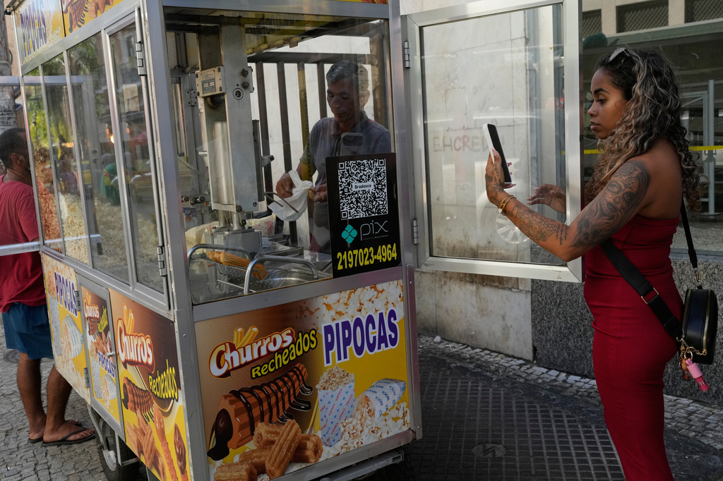 A woman pays for pop corn with the Pix free payment system in Rio de Janeiro, Thursday, April 16, 2026. (AP Photo/Silvia Izquierdo)