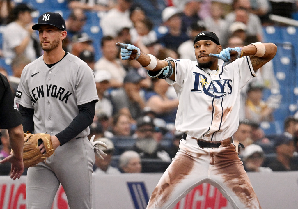 New York Yankees third baseman Ryan McMahon, left, looks away after Tampa Bay Rays' Chandler Simpson, right, slid into third base for a triple during the seventh inning of a baseball game Sunday, April 12, 2026, in St. Petersburg, Fla. (AP Photo/Jason Behnken)