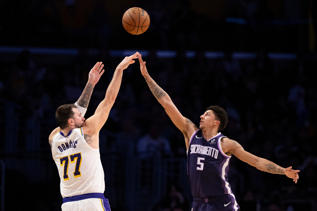 Los Angeles Lakers guard Luka Doncic, left, shoots as Sacramento Kings guard Nique Clifford defends during the first half of an NBA basketball game in Los Angeles, Sunday, March 1, 2026. (AP Photo/Kyusung Gong)