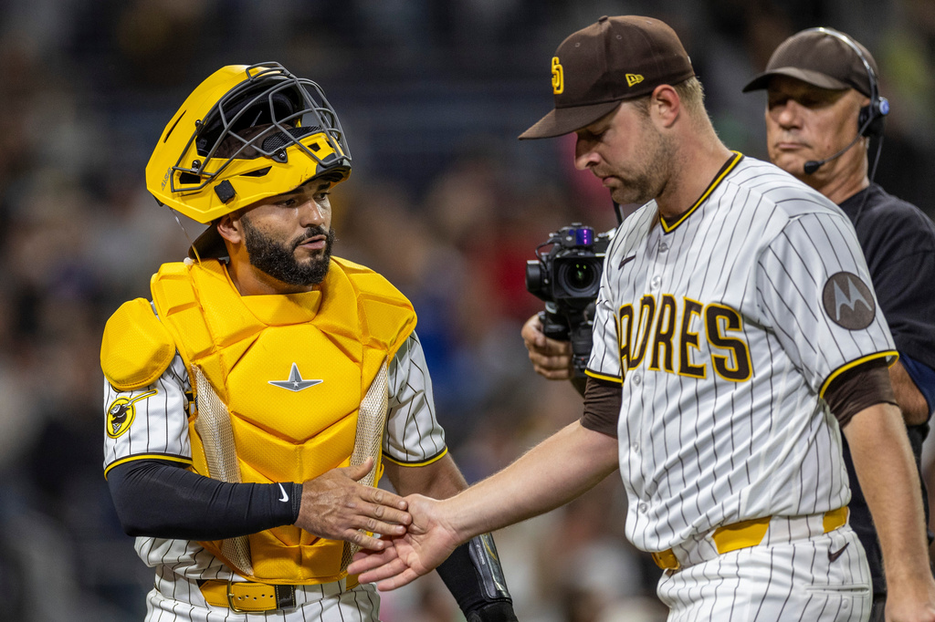San Diego Padres catcher Rodolfo Durán, left, gives a hand to starting pitcher Michael King, front right, after the in the sixth inning of a baseball game against the Los Angeles Dodgers, Monday, May 18, 2026, in San Diego. (AP Photo/Tony Ding)