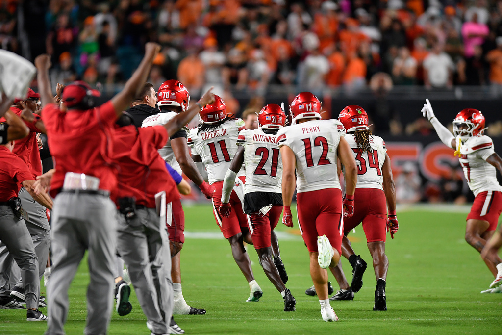 Louisville linebacker T.J.Capers (11) celebrates intercepting a pass with teammates during the second half of an NCAA college football game, against Miami, Friday, Oct. 17, 2025, in Miami Gardens, Fla. (AP Photo/Michael Laughlin)