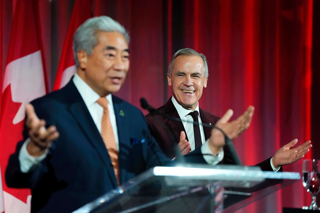Prime Minister Mark Carney reacts as Michael Ma, Member of Parliament for Markham-Unionville, who crossed the floor from the Conservatives to the Liberals hours earlier, makes brief remarks at the Liberal caucus holiday party in Ottawa, on Thursday, Dec. 11, 2025. (Justin Tang/The Canadian Press via AP)