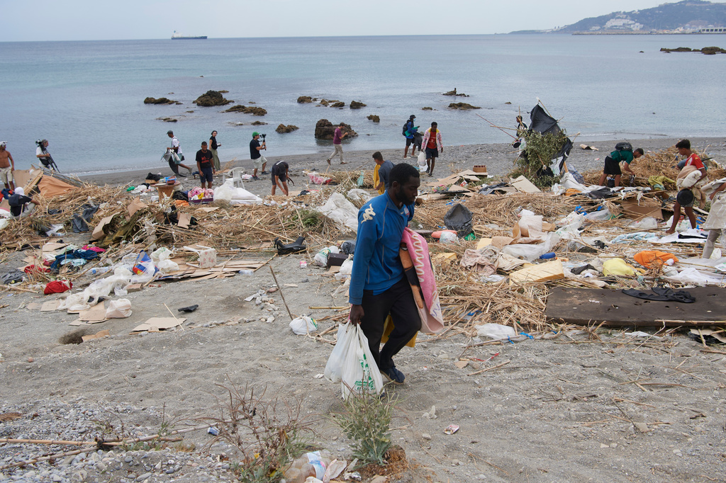 Migrants who crossed from Morocco into Spain gather their belongings after being cleared from the beach in the Spanish exclave of Ceuta, Thursday, Aug. 20, 2026. (AP Photo/Antonio Sempere)
