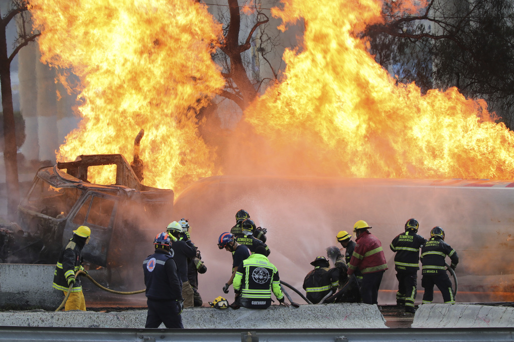 Firefighters spray hoses at a gas tanker that exploded under a highway overpass in Mexico City, Wednesday, Sept. 10, 2025. (AP Photo/Tristan Velazquez)