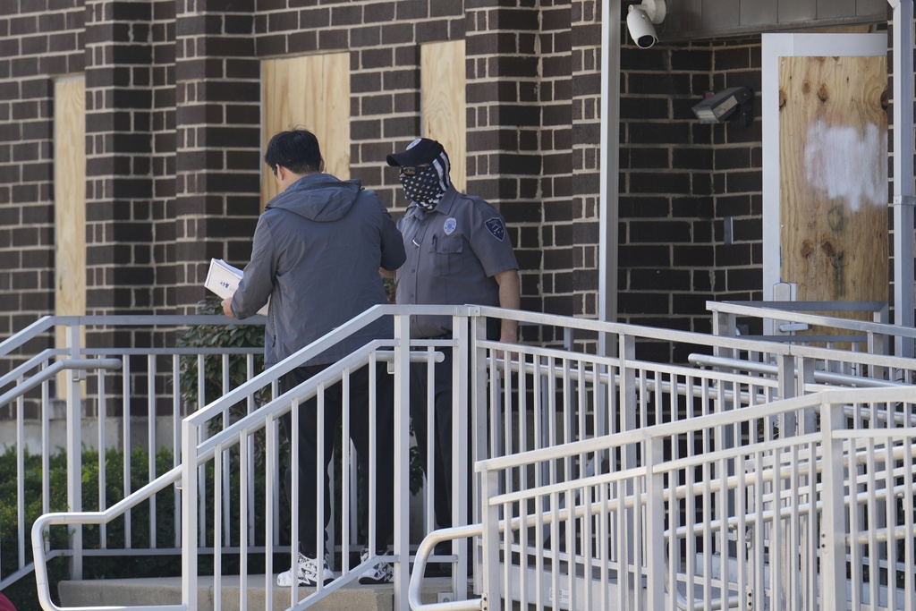 A person talks to a masked guard at the entrance of an immigration processing center Monday, Sept. 8, 2025, in Broadview, Ill., a suburb of Chicago. (AP Photo/Carolyn Kaster)
