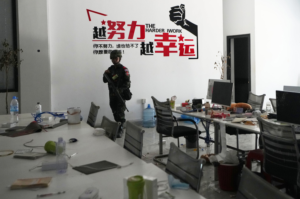 Thai soldier stand front of word motto at work station in scam compound in O'Smach, Cambodia, Tuesday, April 7, 2026. (AP Photo/Sakchai Lalit)