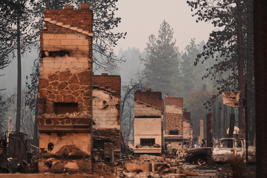 Chimneys are the only structures remaining in a residential neighborhood after a wildfire hit the northern part of Spokane, Wash., Monday, Aug. 3, 2026. (AP Photo/Lindsey Wasson)