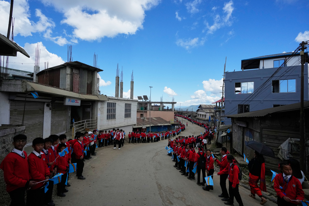 Schoolchildren wait for the arrival of Thuingaleng Muivah, leader of the National Socialist Council of Nagaland (Isak-Muivah), in Ukhrul, in the northeastern Indian state of Manipur, Wednesday, Oct. 22, 2025. (AP Photo/Anupam Nath)