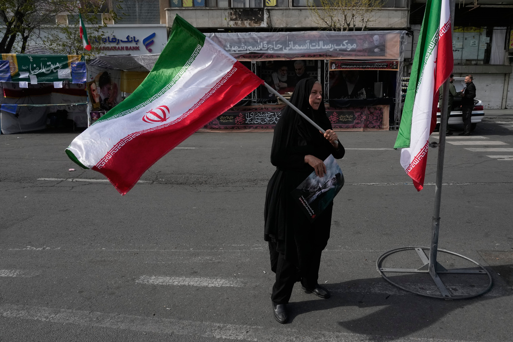 A woman waves an Iranian flag during a campaign in support of the government at the Enqelab-e-Eslami, or Islamic Revolution, square in downtown Tehran, Iran, Sunday, March 22, 2026. (AP Photo/Vahid Salemi)