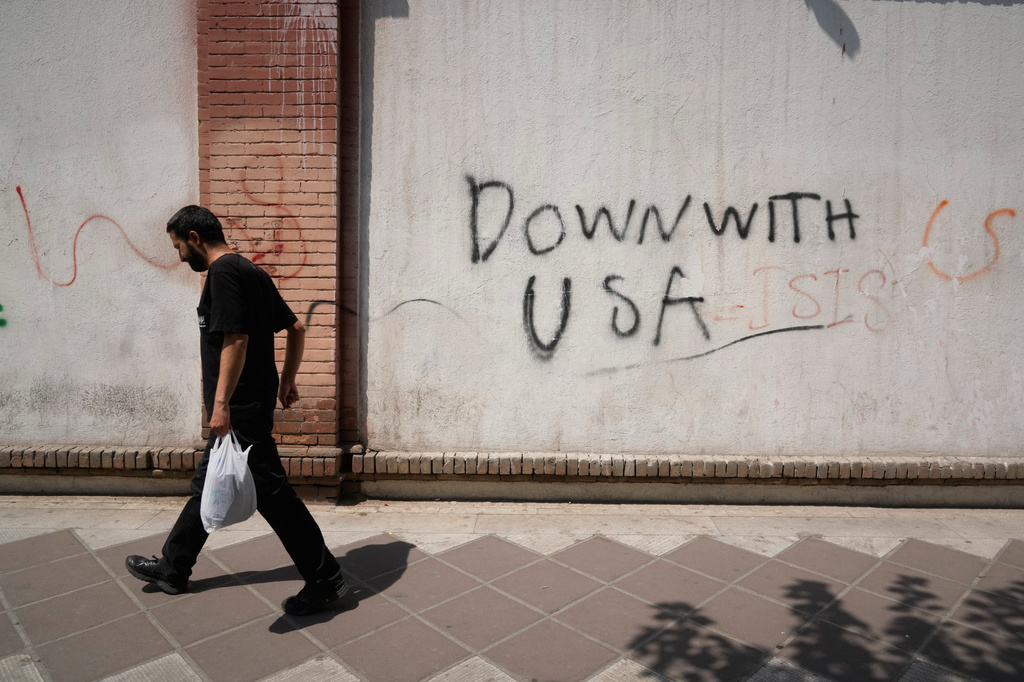 A man walks past anti-U.S. graffiti on the wall of the British Embassy in Tehran, Iran, Monday, July 27, 2026. (AP Photo/Vahid Salemi)