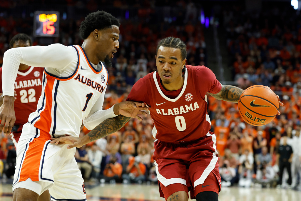 Alabama guard Labaron Philon (0) drives to the basket around Auburn guard Kevin Overton (1) during the first half of an NCAA college basketball game Saturday, Feb. 7, 2026, in Auburn, Ala. (AP Photo/Butch Dill)