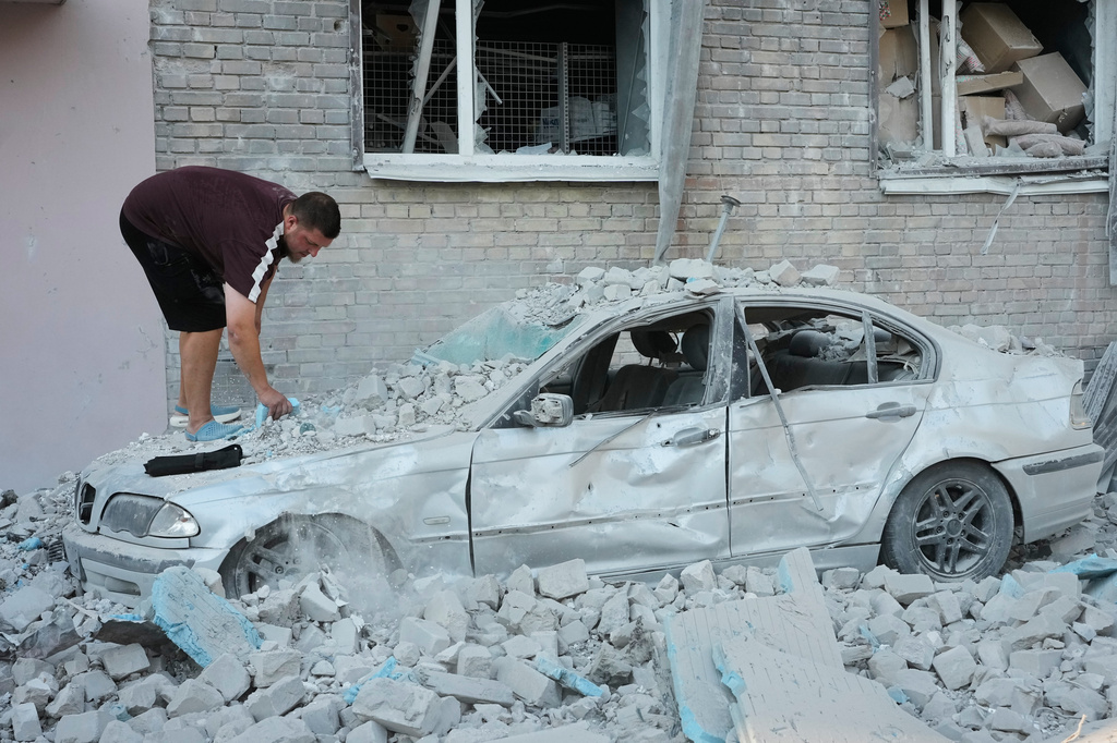 A local resident inspects a damaged car after a Russian strike on Kyiv, Ukraine, Thursday, July 2, 2026. (AP Photo/Efrem Lukatsky)