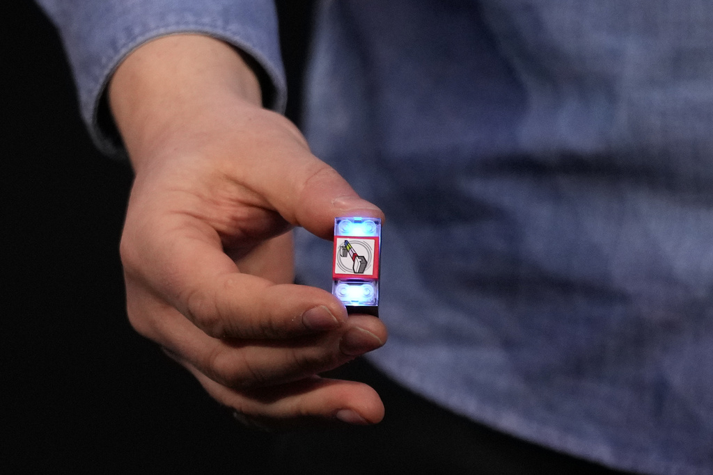 A LEGO smart brick is held during a LEGO news conference ahead of the CES tech show Monday, Jan. 5, 2026, in Las Vegas. (AP Photo/Abbie Parr)
