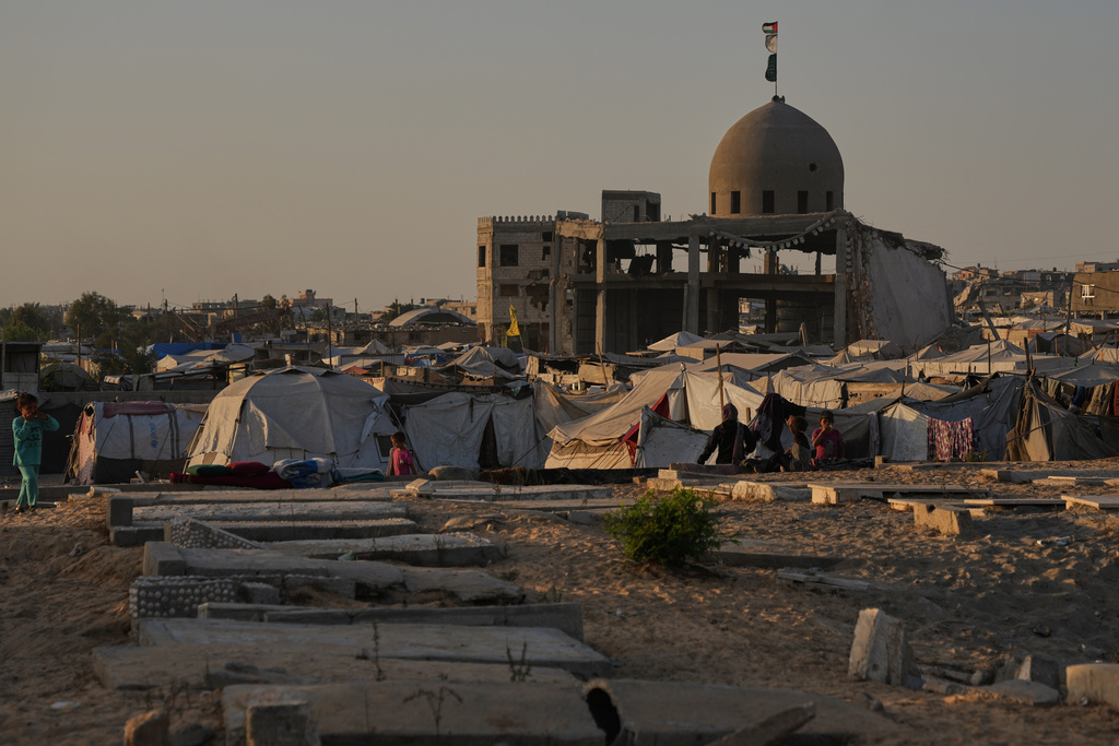 Palestinians stand near makeshift tents for displaced people, which were set up next to graves in a cemetery in Khan Younis, in the southern Gaza Strip, Friday, Oct. 31, 2025. (AP Photo/Abdel Kareem Hana)