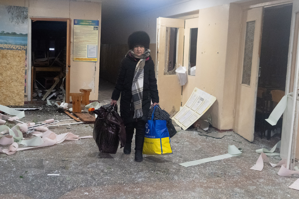 A resident leaves her home in a damaged building following a Russian drone attack in Kharkiv, Ukraine, Saturday, Jan. 24, 2026. (AP Photo/Andrii Marienko)