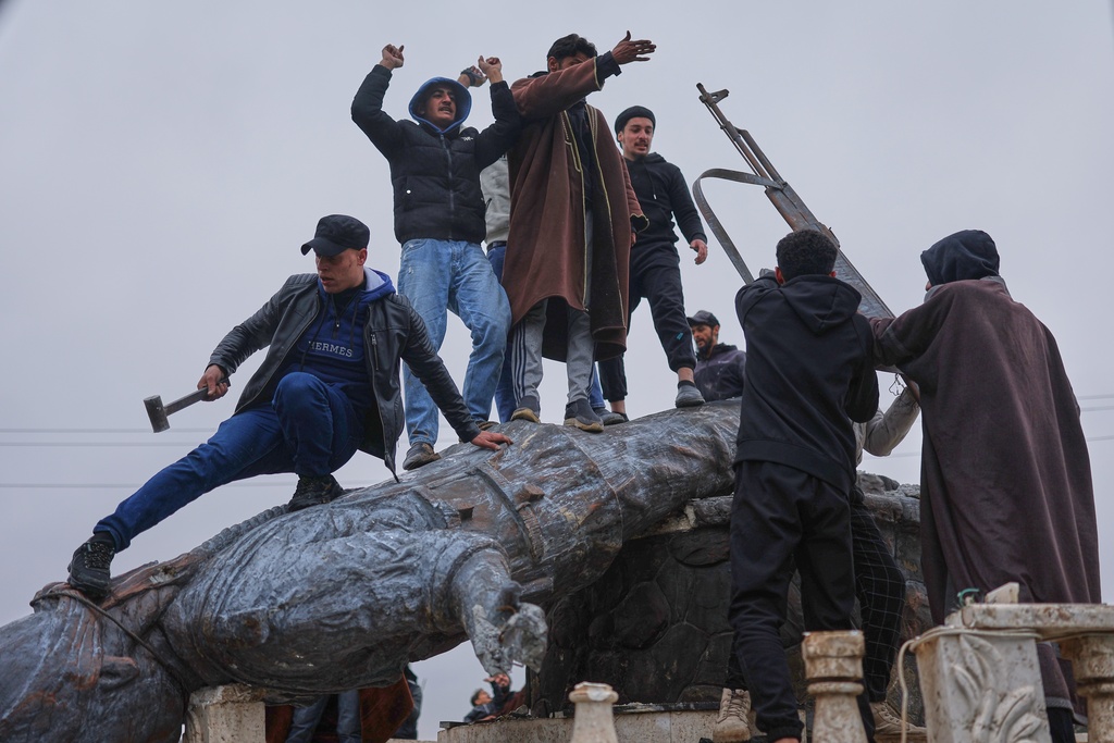 Residents topple a statue of a female Kurdish fighter after the takeover of the town by Syrian government forces from U.S.-backed Syrian Democratic Forces (SDF), in Tabqa, eastern Syria, Sunday, Jan. 18, 2026. (AP Photo/Ghaith Alsayed)