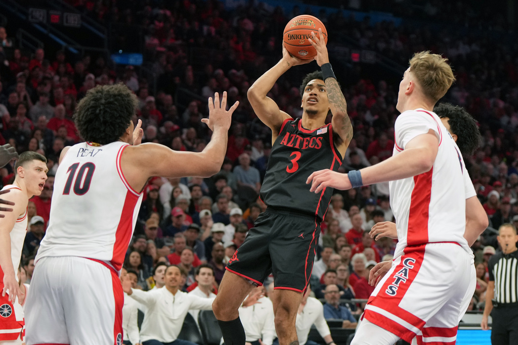San Diego State guard Elzie Harrington (3) looks to shoot between Arizona forward Koa Peat (10) and center Motiejus Krivas, front right, during the first half of an NCAA college basketball game, Saturday, Dec. 20, 2025, in Phoenix. (AP Photo/Rick Scuteri)