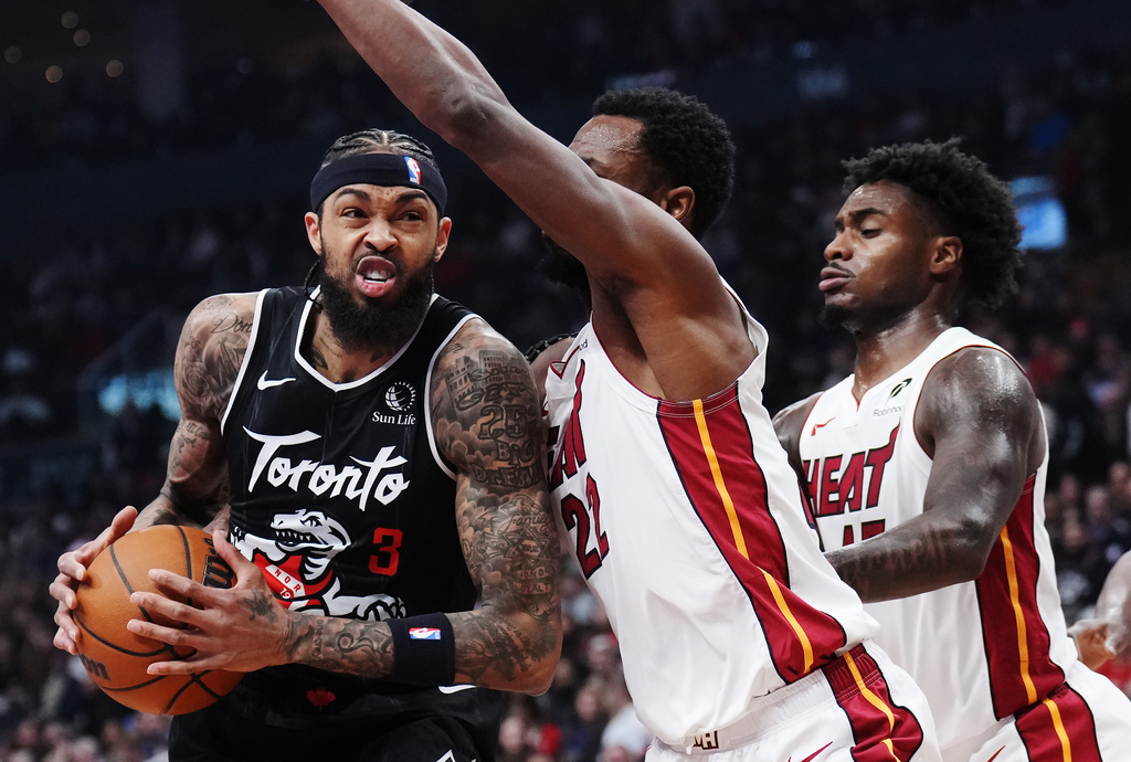 Toronto Raptors' Brandon Ingram (3) drives as Miami Heat's Andrew Wiggins (22) defends during first-half NBA basketball game action in Toronto, Thursday, April 9, 2026. (Nathan Denette/The Canadian Press via AP)