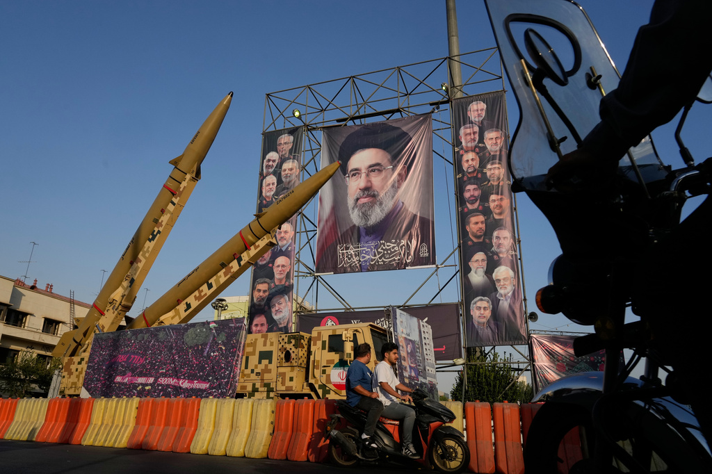 Motorbikes drive past Iranian missiles and banners showing portraits of the Iranian Supreme Leader Ayatollah Mojtaba Khamenei, center, and the late armed forces commanders and nuclear scientists, who were killed in Israeli and U.S. strikes, displayed in a military exhibition commemorating the anniversary of the start of the 1980-88 Iraq-Iran war at Baharestan Square, in Tehran, Monday, Sept. 28, 2026. (AP Photo/Vahid Salemi)
