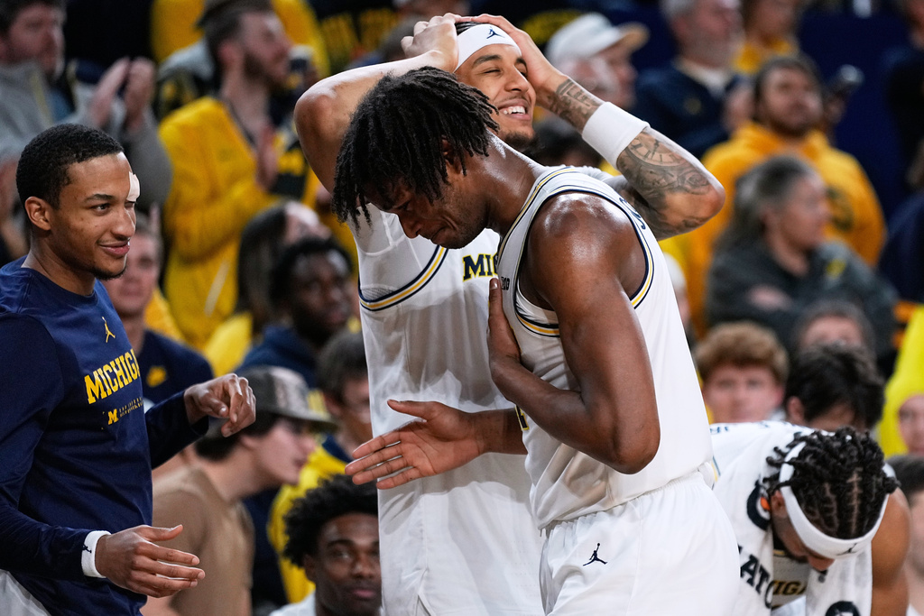 Michigan forward Morez Johnson Jr., front right, greets guard Nimari Burnett, left, and forward Yaxel Lendeborg, back right, on the bench during the second half of an NCAA college basketball game against Southern California, Friday, Jan. 2, 2026, in Ann Arbor, Mich. (AP Photo/Ryan Sun)