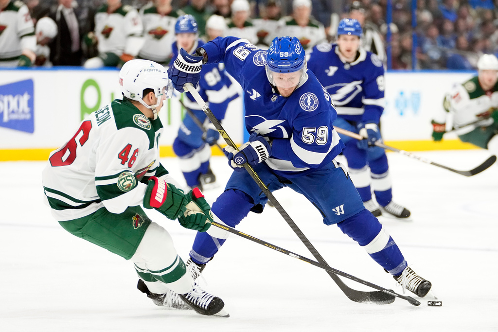 Minnesota Wild defenseman Jared Spurgeon (46) knocks the puck away from Tampa Bay Lightning center Jake Guentzel (59) during the second period of an NHL hockey game Tuesday, March 24, 2026, in Tampa, Fla. (AP Photo/Chris O'Meara)