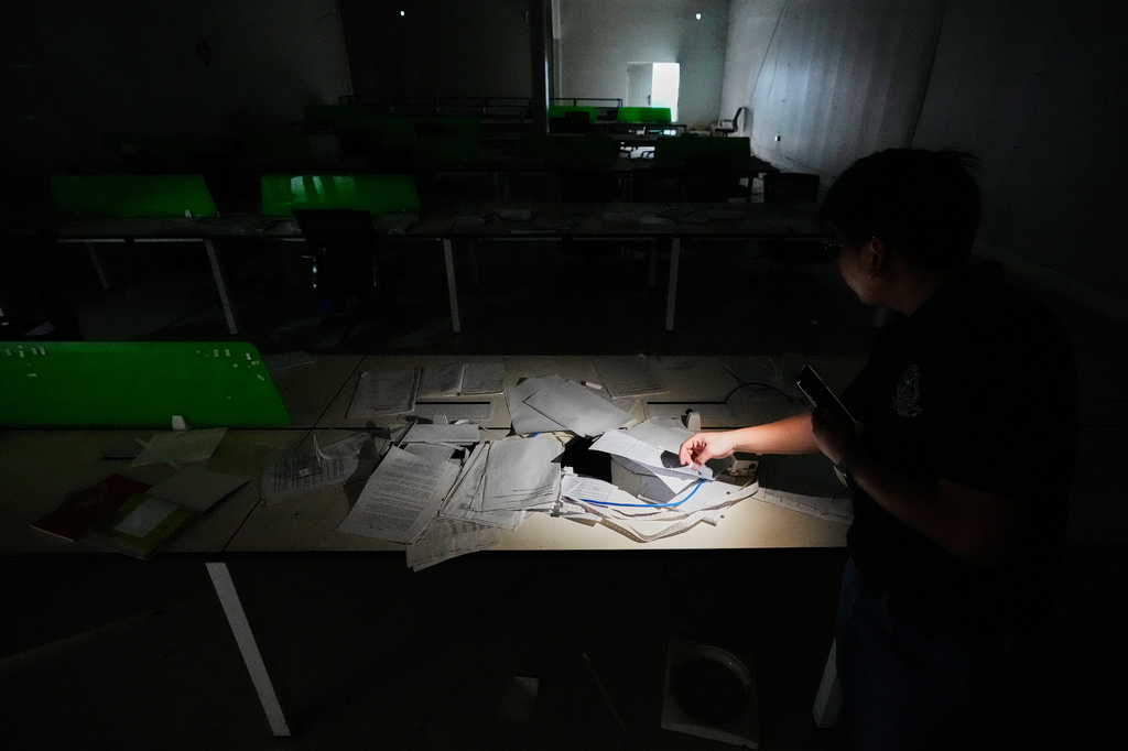 An officer of the Presidential Anti-Organized Crime Commission looks at notes left behind at the sprawling former Baofu scam compound after authorities raided it last year in Bamban, Tarlac city, northern Philippines, Thursday, June 5, 2025. (AP Photo/Aaron Favila)